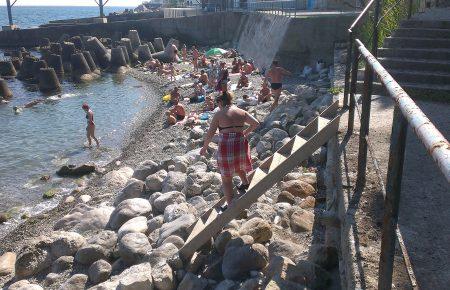 Отдыхающие в Алупке пробираются на пляж по разбитым лестницам и через горы мусора